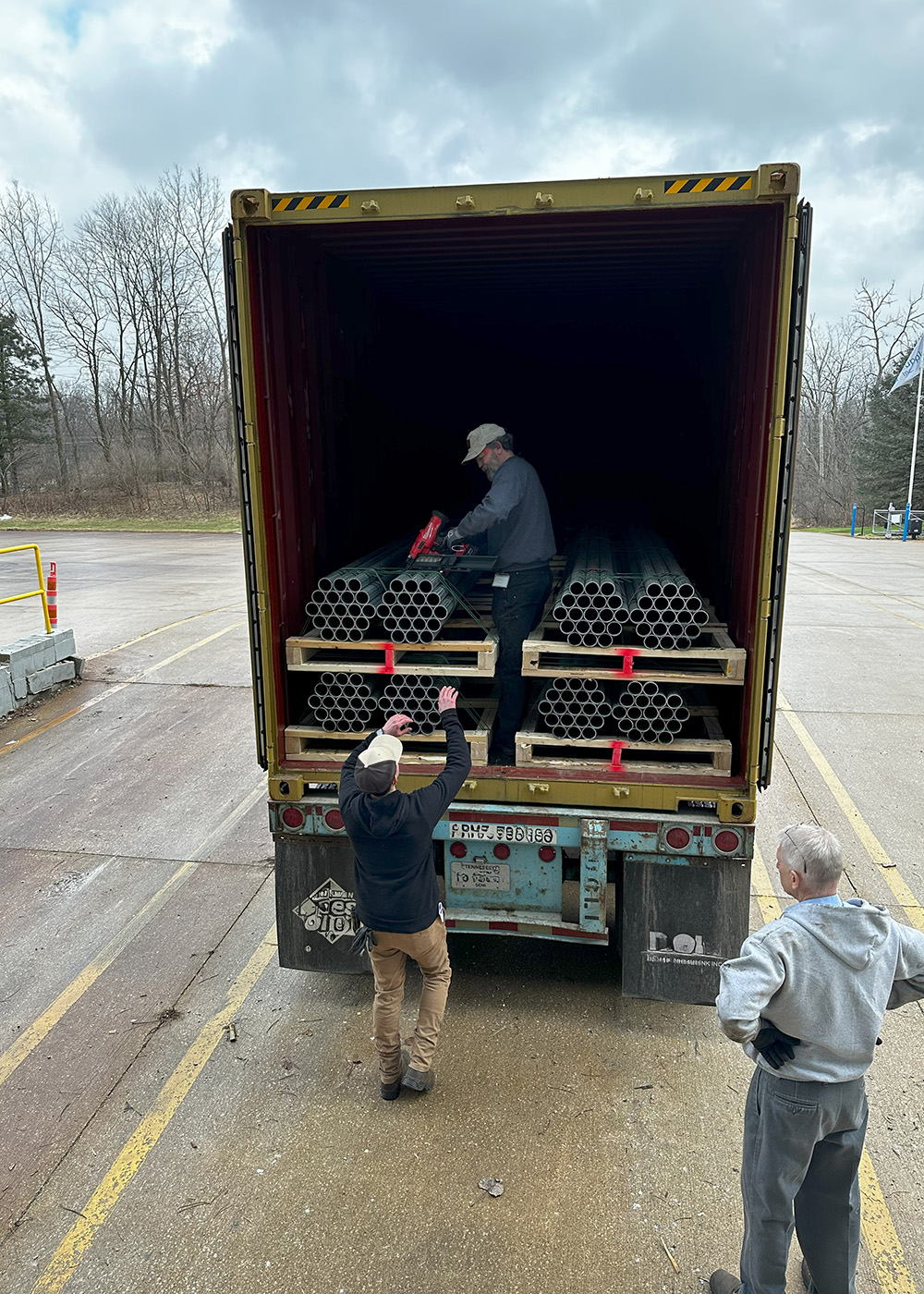 Men loading chain link fence order onto truck container