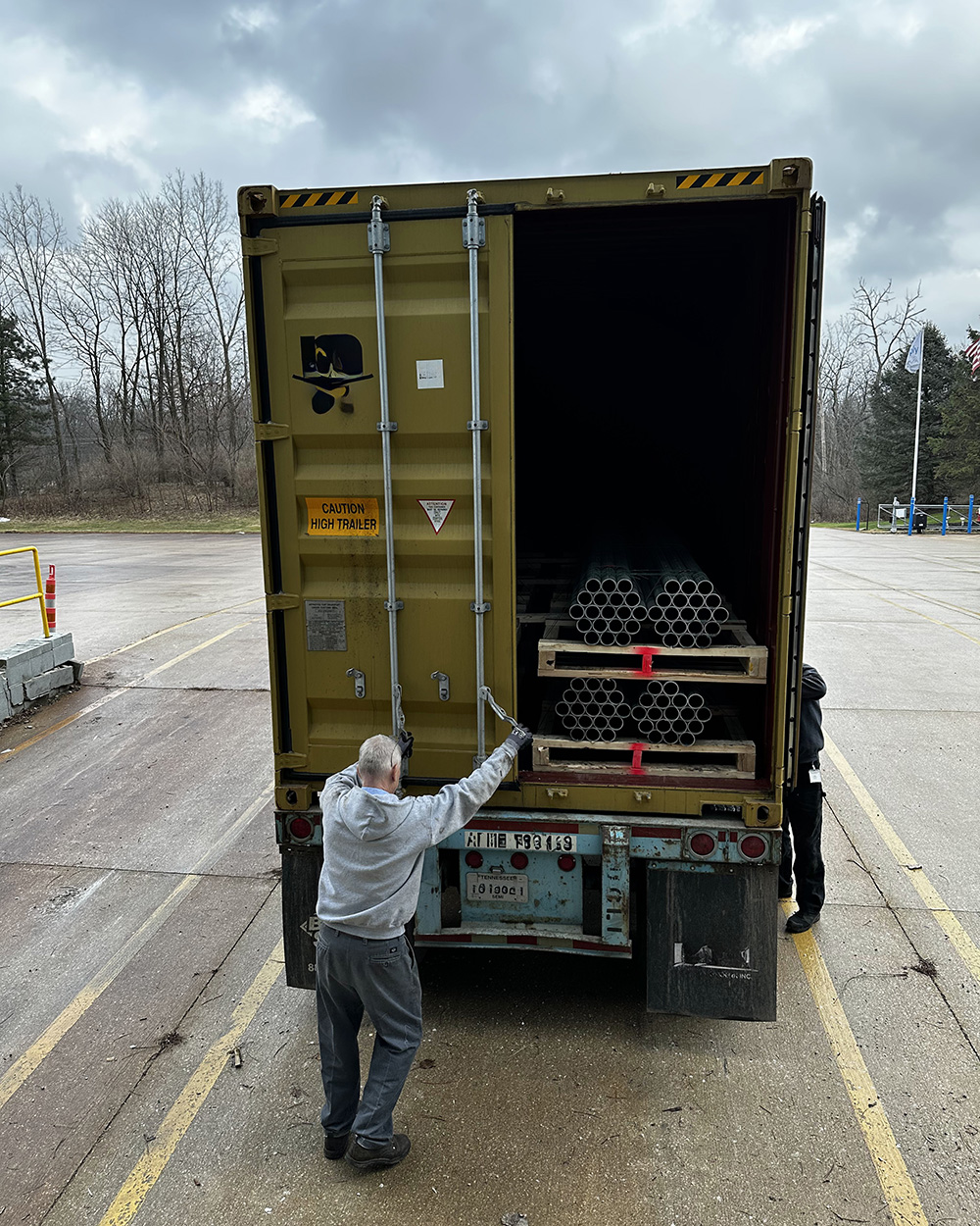 Man closing the door of a truck loaded with chain link mesh and fittings